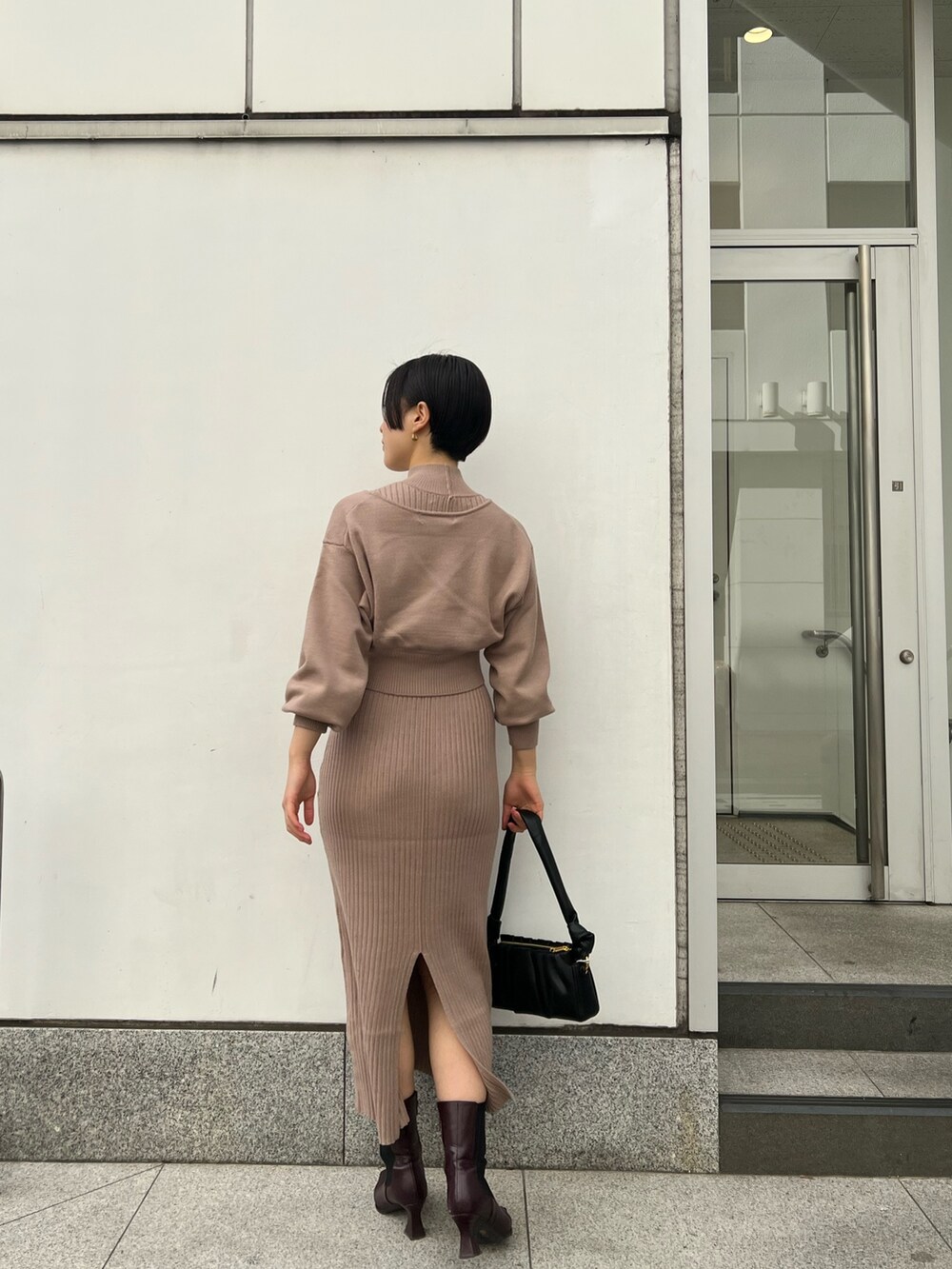 レッド系のブーツ、ブラック系のハンドバッグ、ベージュ系のワンピースを着用したレディースの冬コーディネートの6枚目の写真