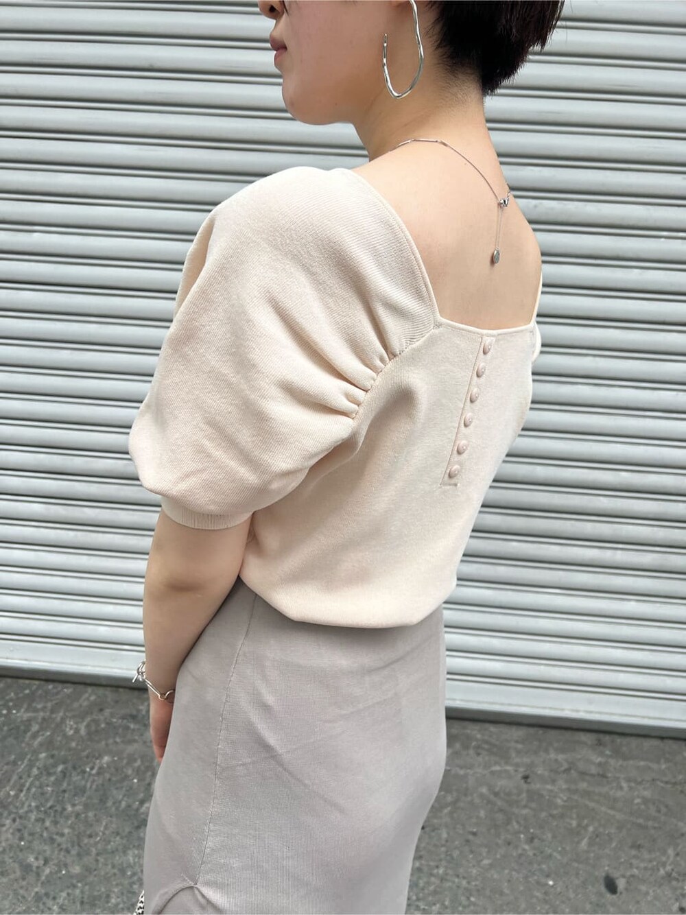 ブラウン系のパンプス、ホワイト系のニット/セーター、ホワイト系のハンドバッグを着用したレディースの夏コーディネートの6枚目の写真