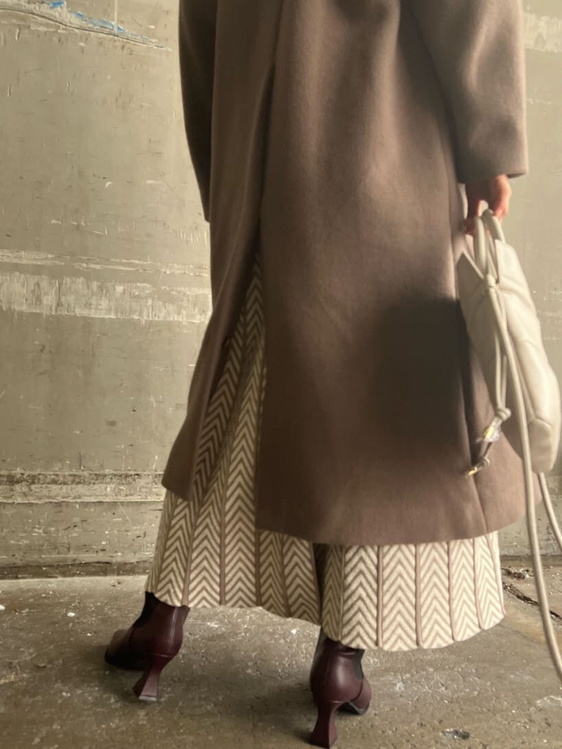 レッド系のブーツ、ベージュ系のワンピース、ホワイト系のハンドバッグを着用したレディースの秋コーディネートの5枚目の写真