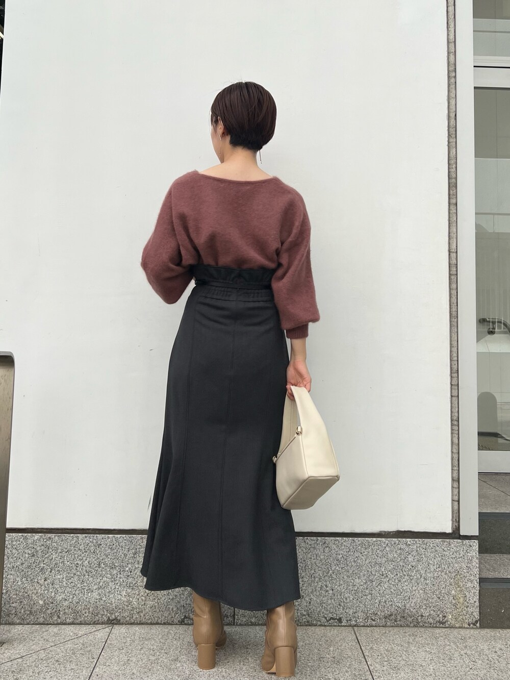 ホワイト系のハンドバッグ、グレー系のスカート、ベージュ系のブーツを着用したレディースの秋コーディネートの6枚目の写真