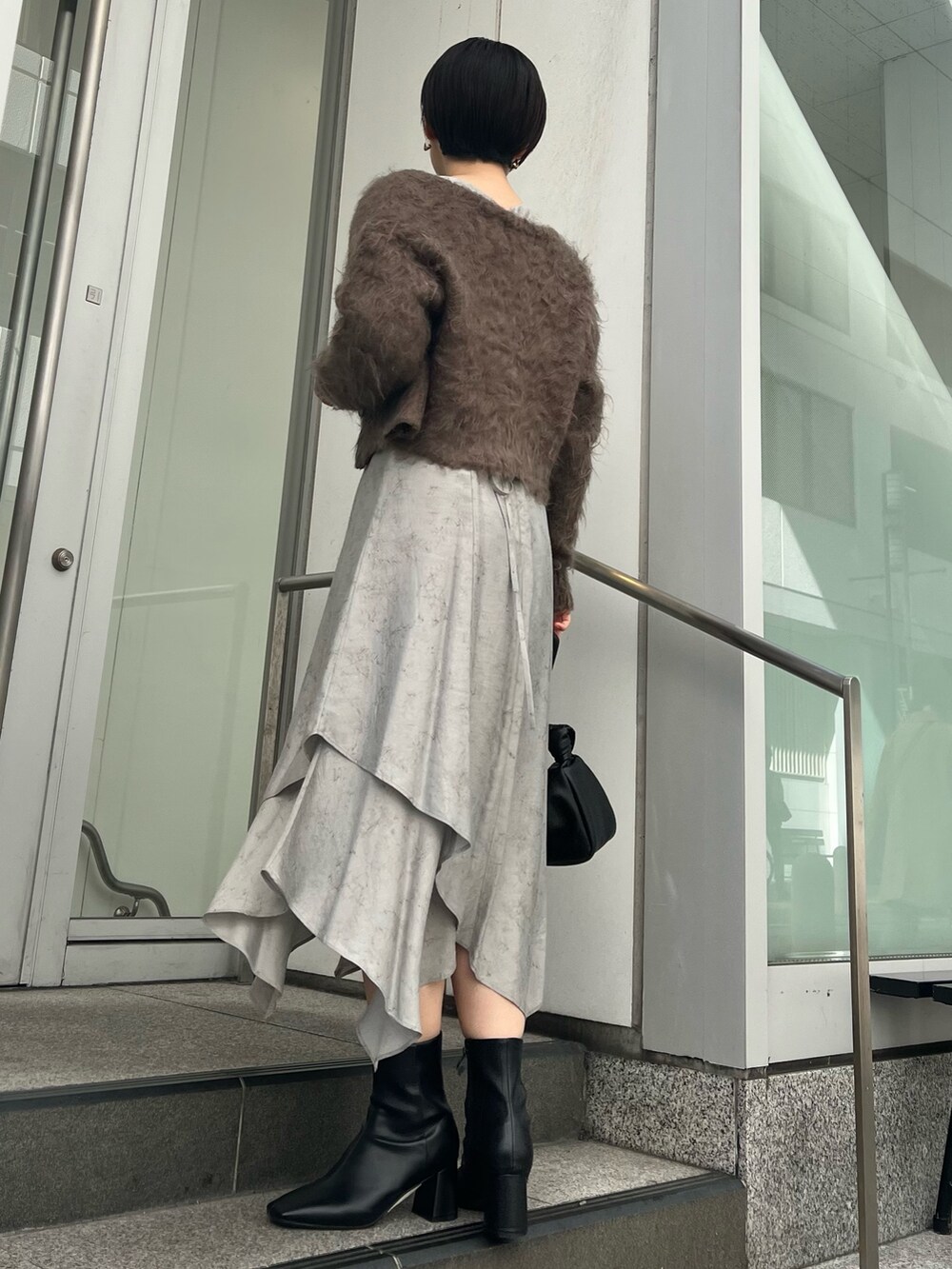 グレー系のカーディガン/ボレロ、グレー系のワンピース、ブラック系のブーツを着用したレディースの秋コーディネートの3枚目の写真