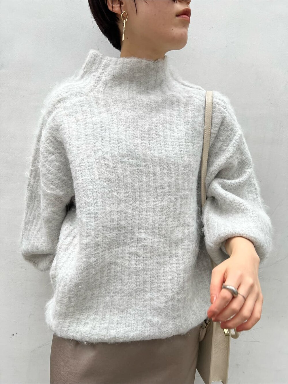 ベージュ系のスカート、ホワイト系のショルダーバッグ、ベージュ系のその他シューズを着用したレディースの冬コーディネートの3枚目の写真