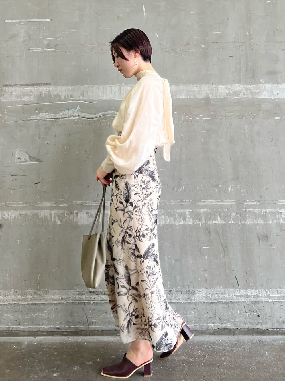 ベージュ系のハンドバッグ、ベージュ系のスカート、ブラウン系のシャツ/ブラウスを着用したレディースの夏コーディネートの2枚目の写真