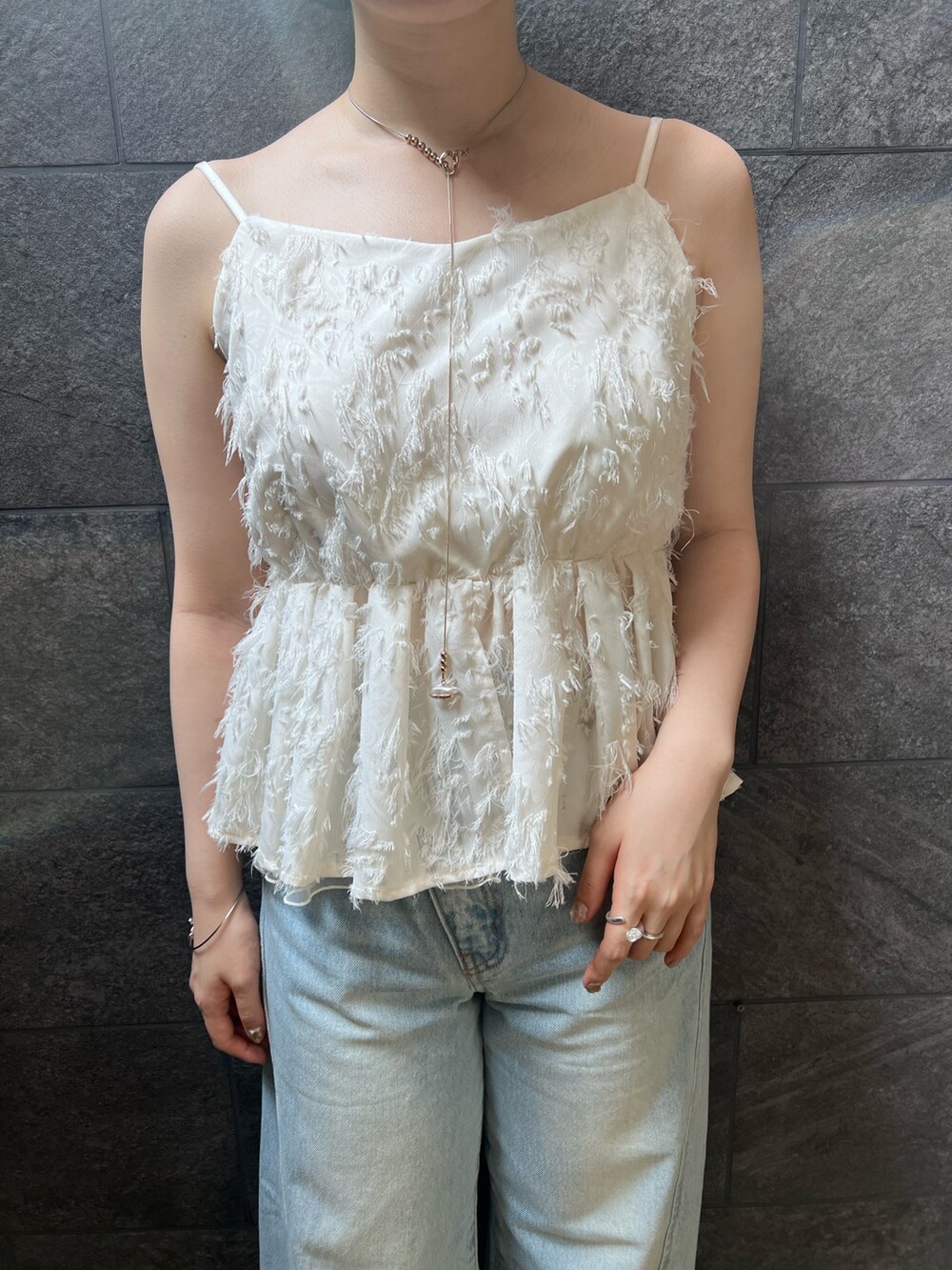 ホワイト系のサンダル、ホワイト系のキャミソール、ブルー系のデニムパンツを着用したレディースの夏コーディネートの3枚目の写真