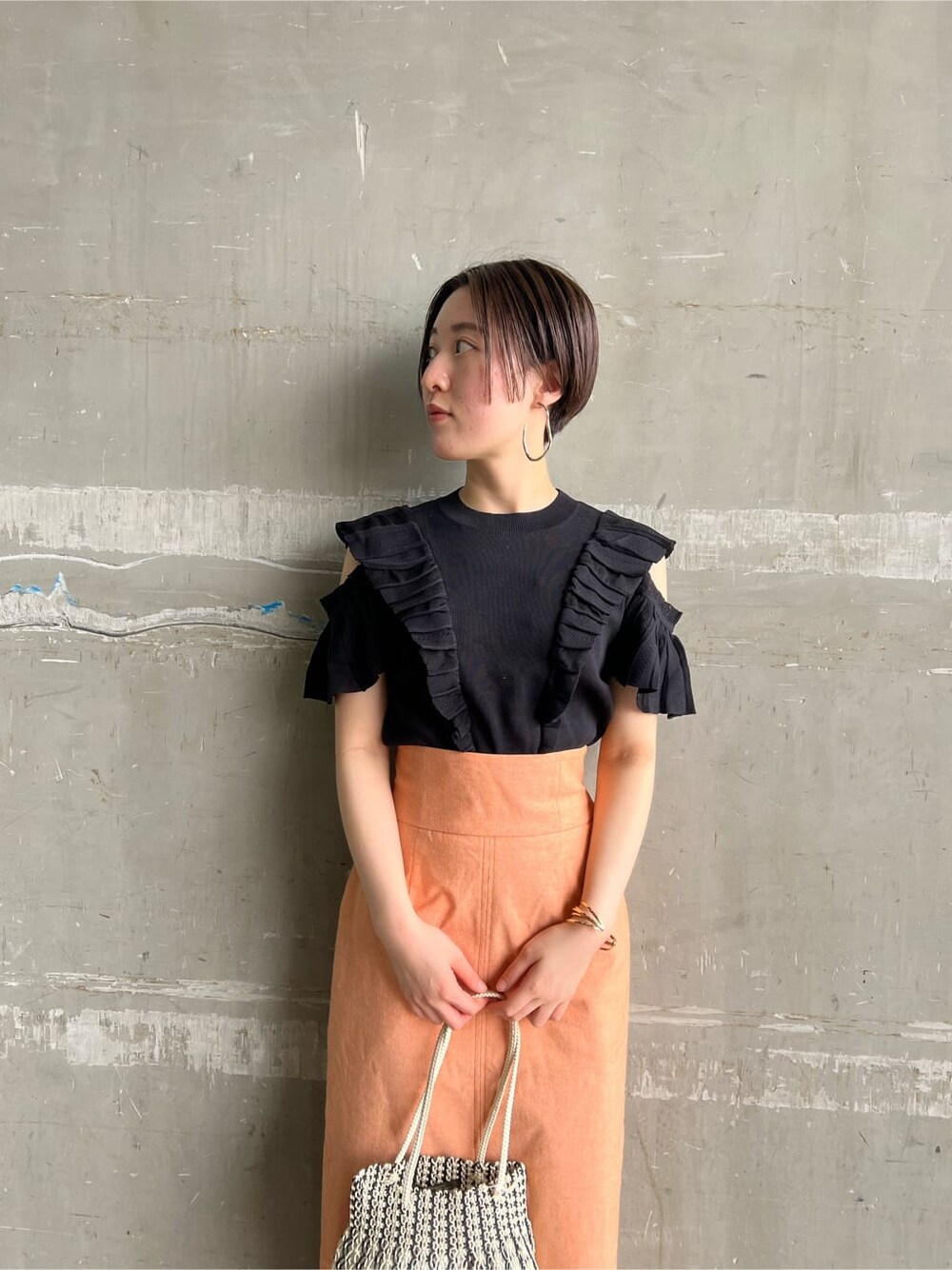 オレンジ系のスカート、その他のパンプス、ブラック系のニット/セーターを着用したレディースの春コーディネートの6枚目の写真