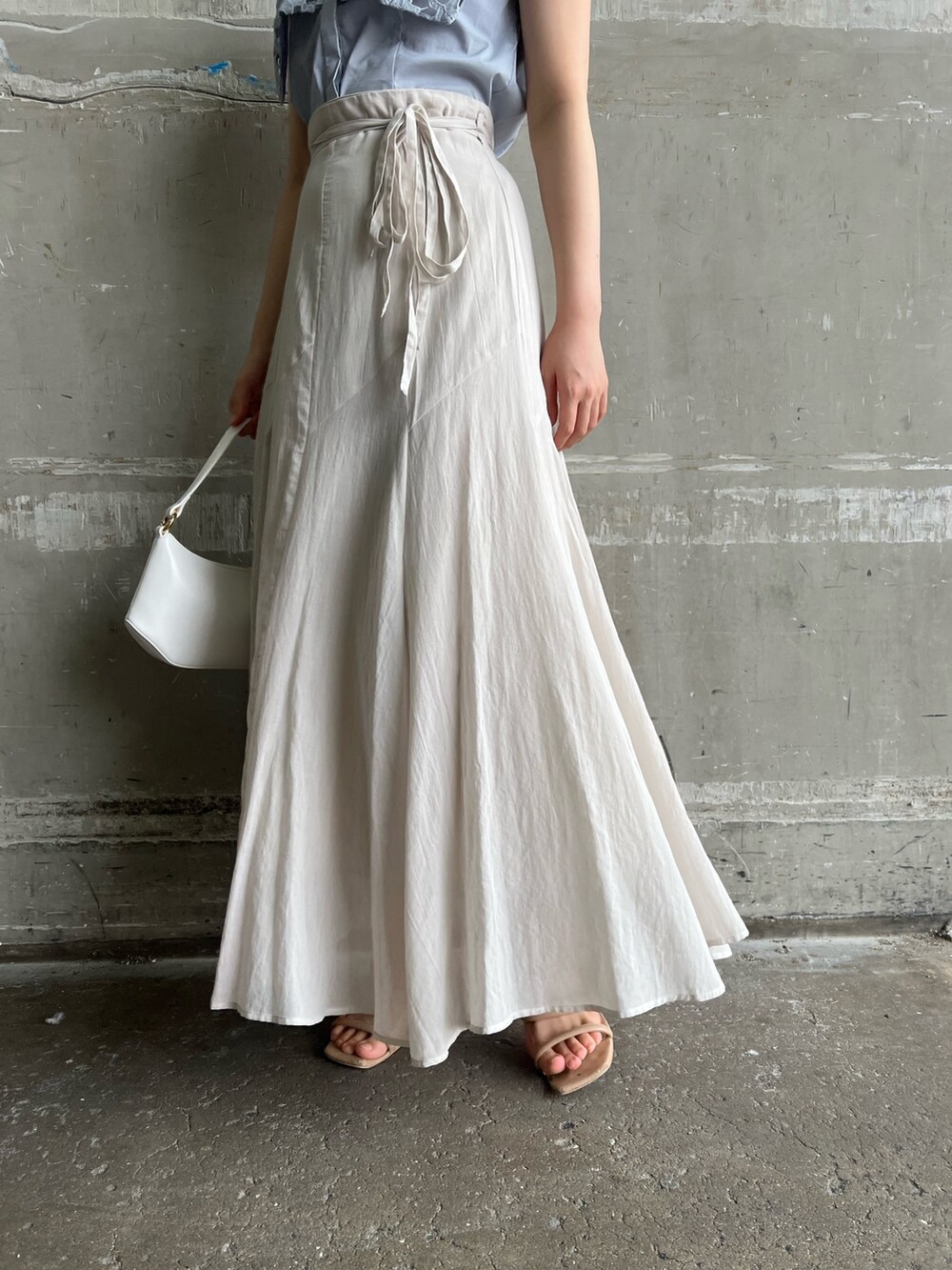 ベージュ系のサンダル、ホワイト系のハンドバッグ、グレー系のスカートを着用したレディースの夏コーディネートの6枚目の写真