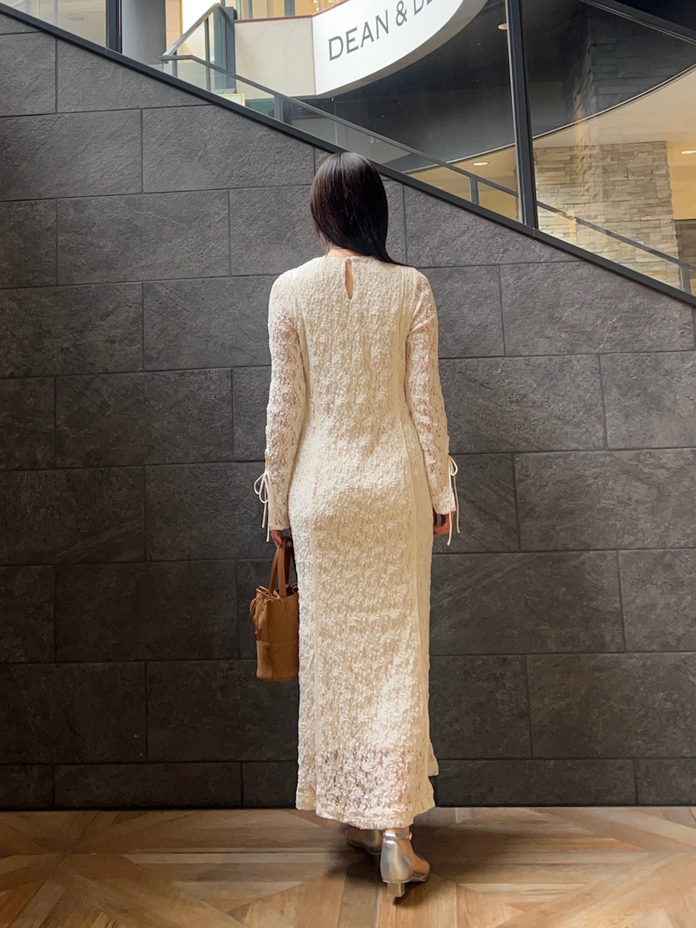 ホワイト系のワンピース、ブラウン系のハンドバッグ、シルバー系のパンプスを着用したレディースの冬コーディネートの3枚目の写真