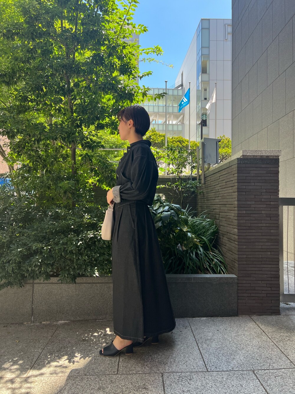 ブラック系のデニムジャケット、ブルー系のニット/セーター、ホワイト系のハンドバッグを着用したレディースの秋コーディネートの2枚目の写真