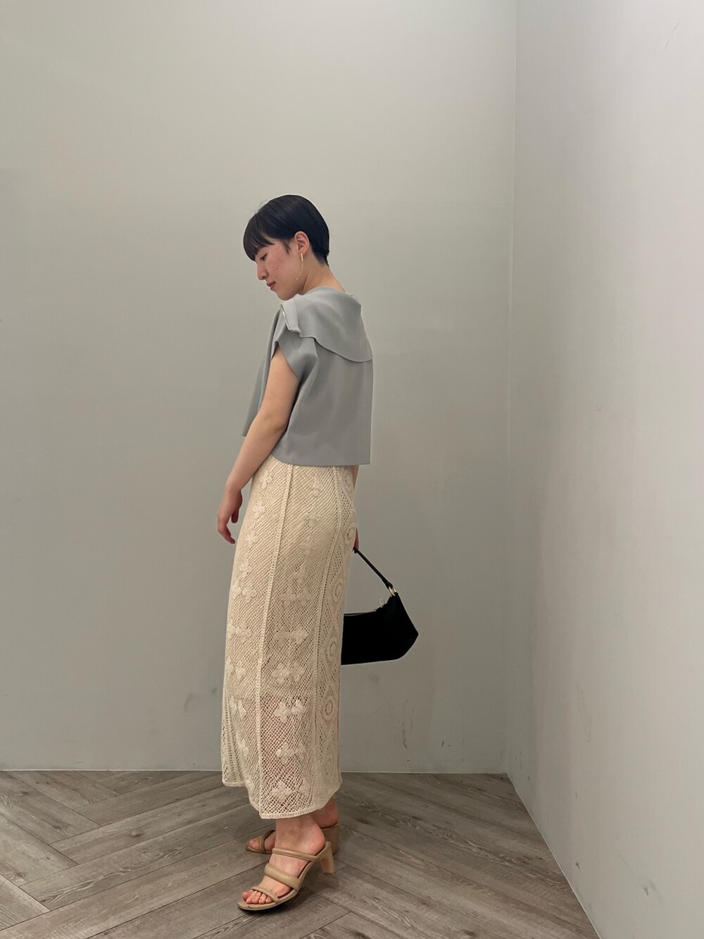 ベージュ系のサンダル、ブラック系のハンドバッグ、ブルー系のニット/セーターを着用したレディースの春コーディネートの2枚目の写真