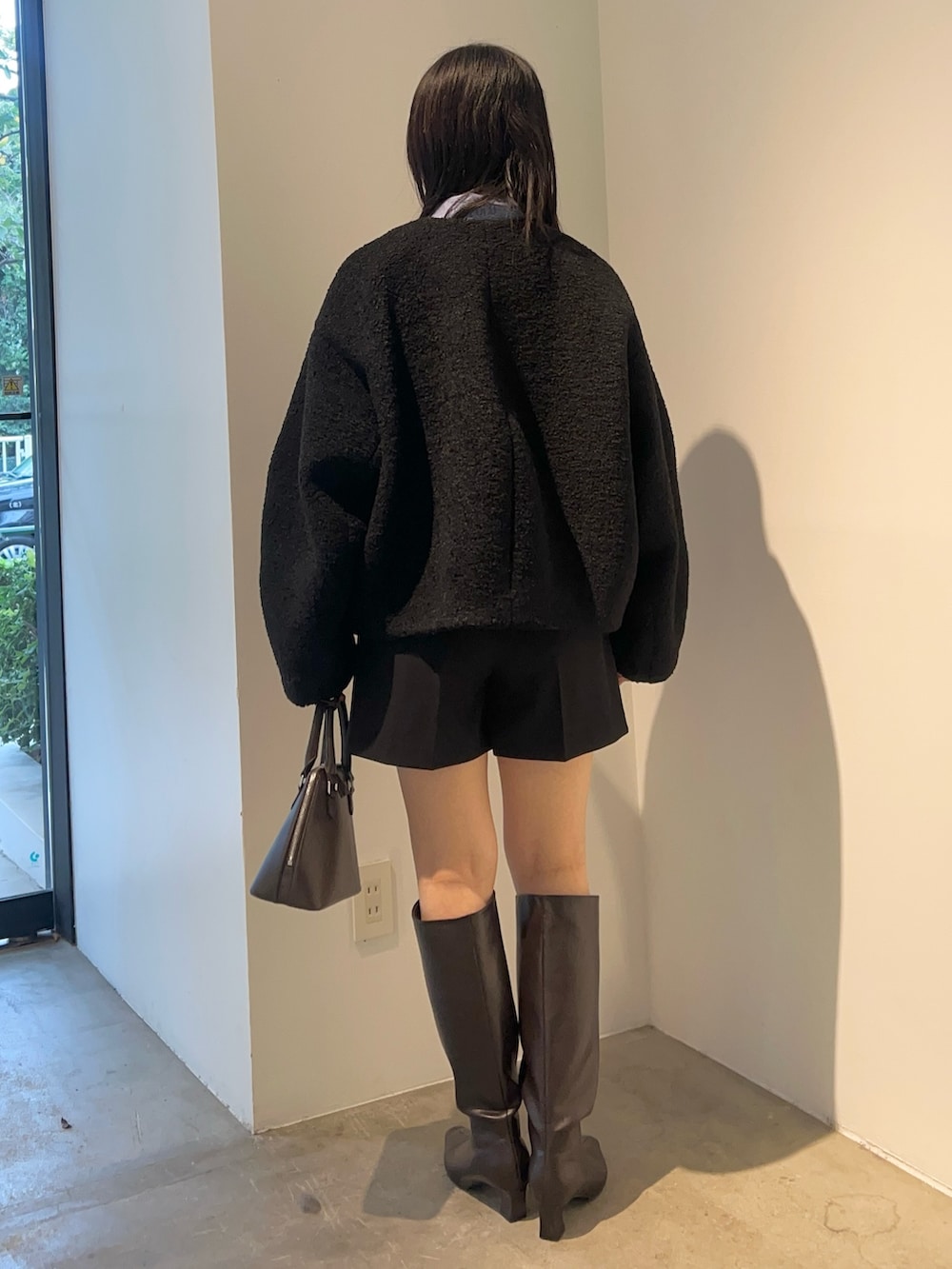 ブラウン系のブーツ、ブラック系のブルゾン、ブラウン系のニット/セーターを着用したレディースの秋コーディネートの3枚目の写真