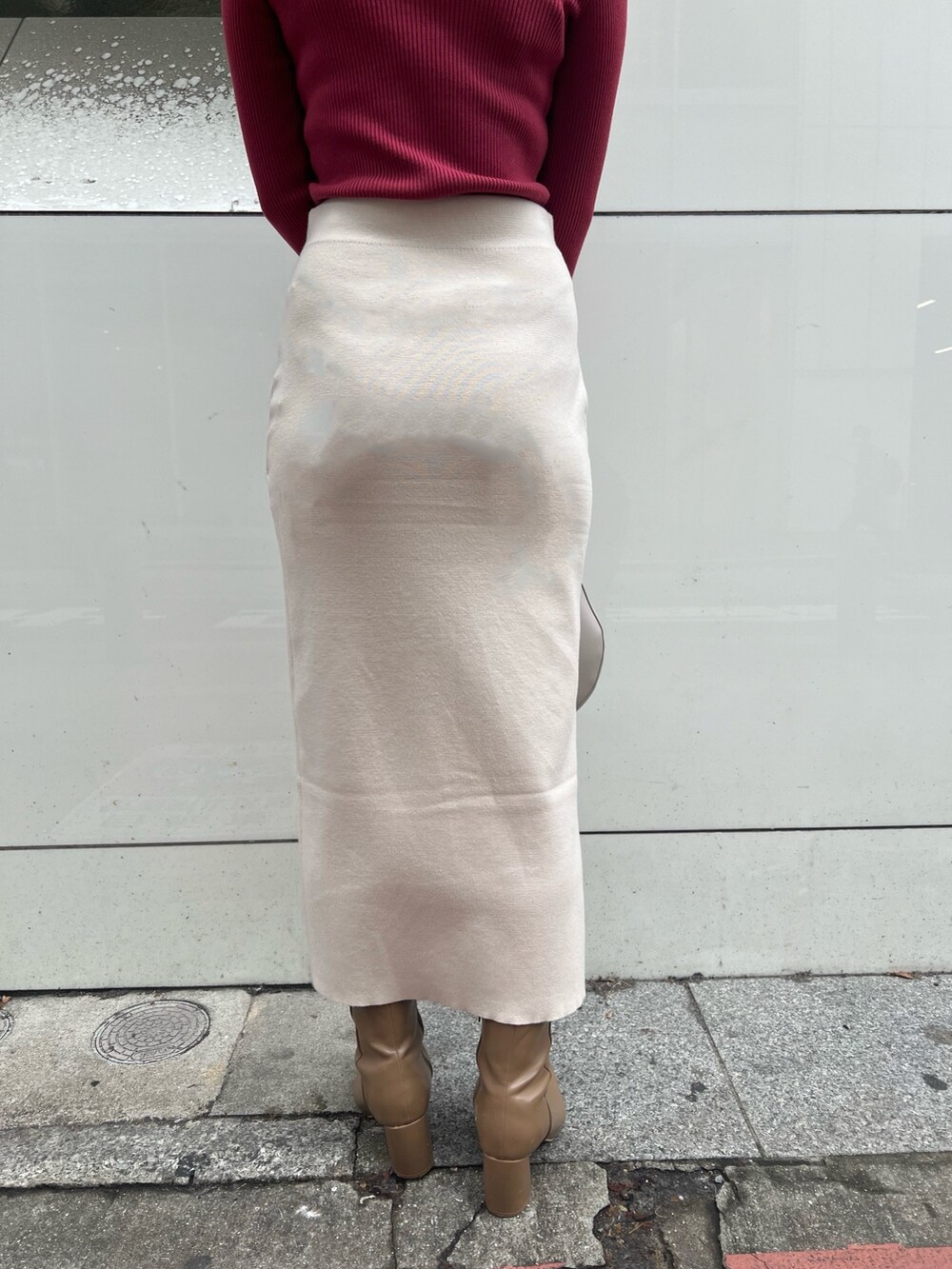 グレー系のノーカラーコート、ベージュ系のブーツ、ホワイト系のハンドバッグを着用したレディースの冬コーディネートの8枚目の写真