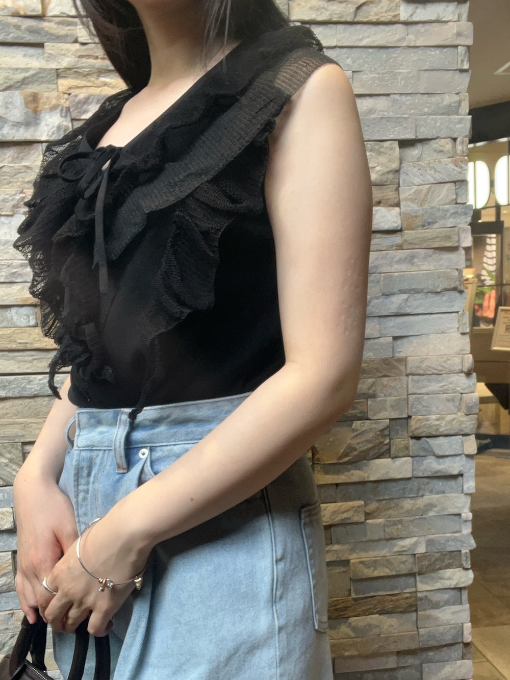 ブラック系のニット/セーター、ベージュ系のパンプス、ブラウン系のボストンバッグを着用したレディースの夏コーディネートの4枚目の写真