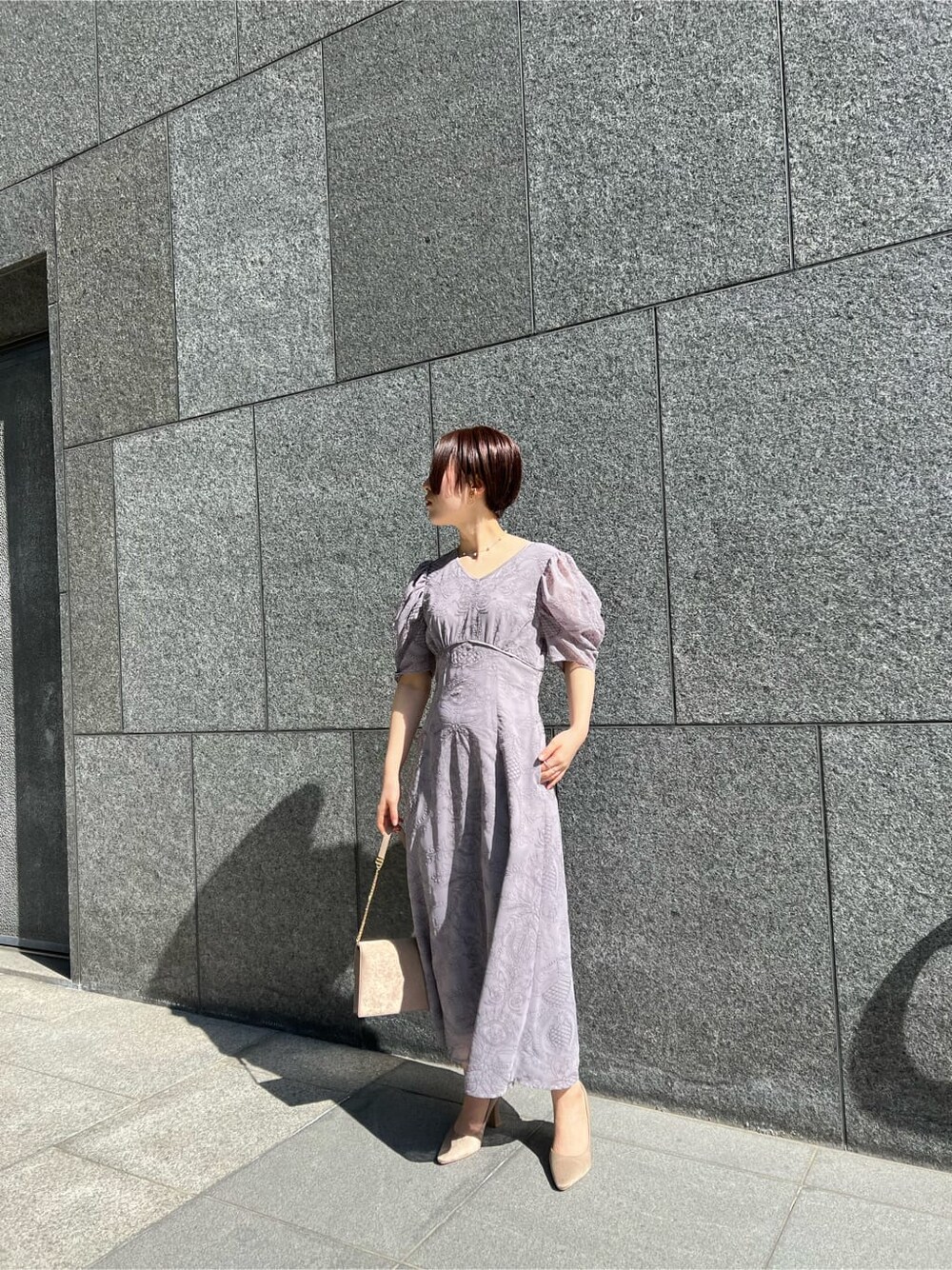 ブラウン系のクラッチバッグ、ベージュ系のその他アウター、パープル系のドレスを着用したレディースの冬コーディネートの3枚目の写真