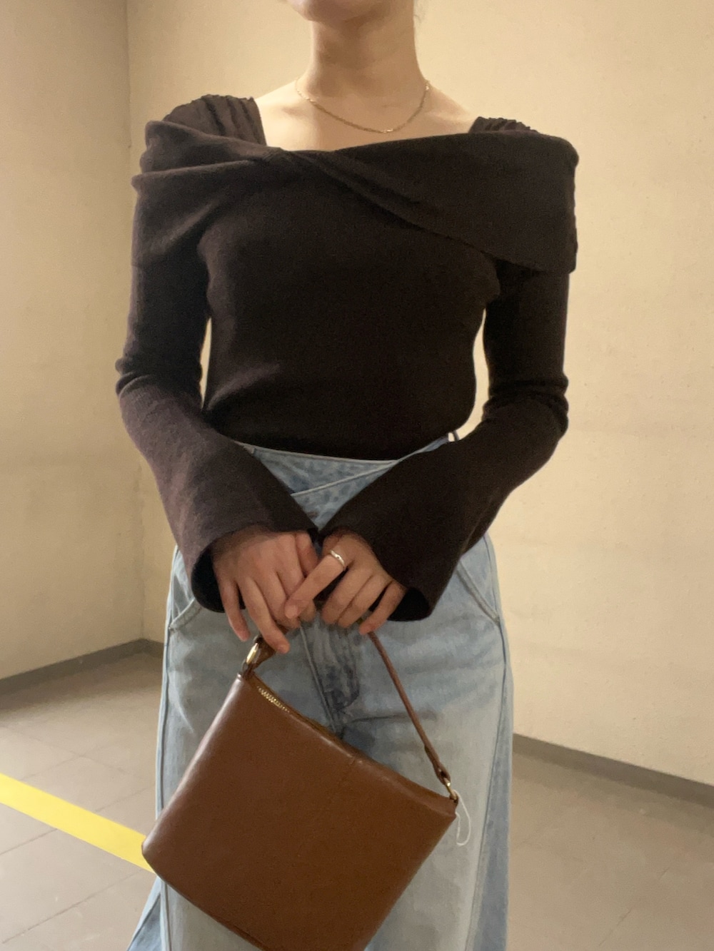 ブルー系のデニムパンツ、ブラウン系のニット/セーター、イエロー系のハンドバッグを着用したレディースの冬コーディネートの4枚目の写真