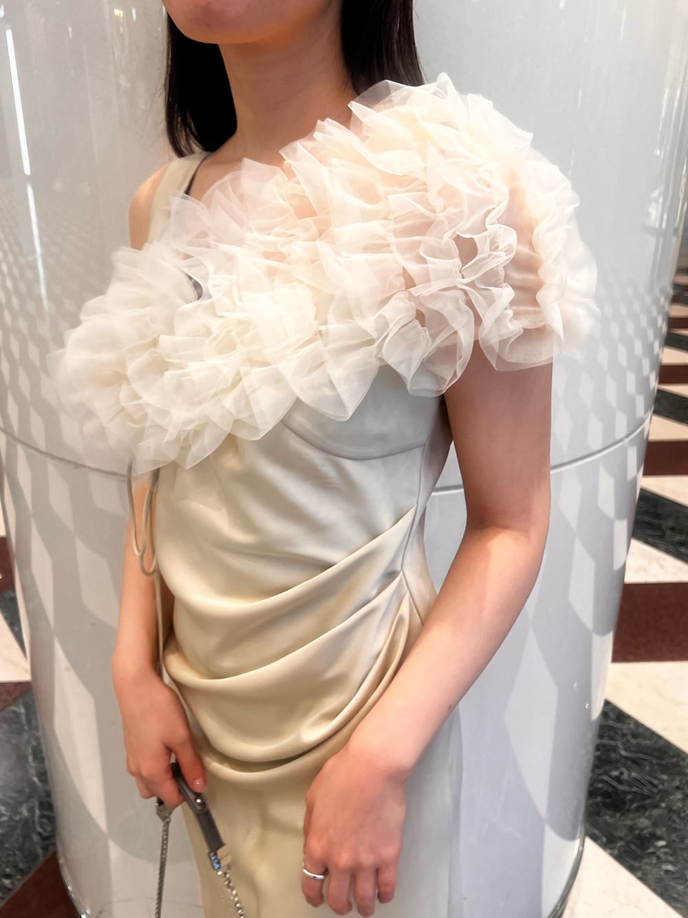 グレー系のテーラードジャケット、イエロー系のドレス、シルバー系のクラッチバッグを着用したレディースの冬コーディネートの5枚目の写真