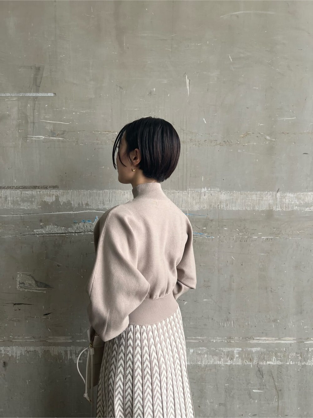 レッド系のブーツ、ベージュ系のワンピース、ホワイト系のハンドバッグを着用したレディースの秋コーディネートの9枚目の写真