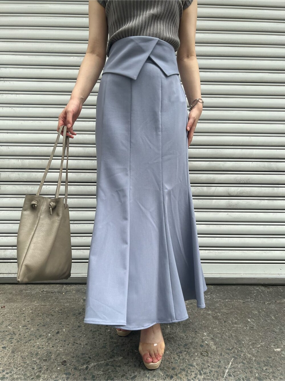 ベージュ系のハンドバッグ、その他のパンプス、ブルー系のスカートを着用したレディースの夏コーディネートの4枚目の写真