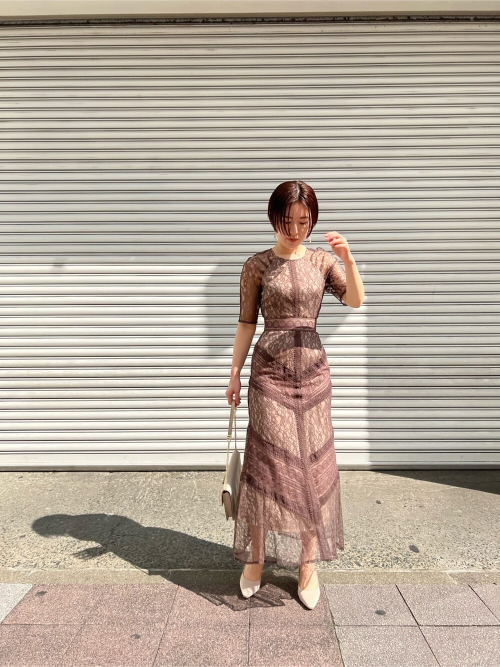 ホワイト系のノーカラーコート、ベージュ系のドレス、ベージュ系のクラッチバッグを着用したレディースの春コーディネートの3枚目の写真