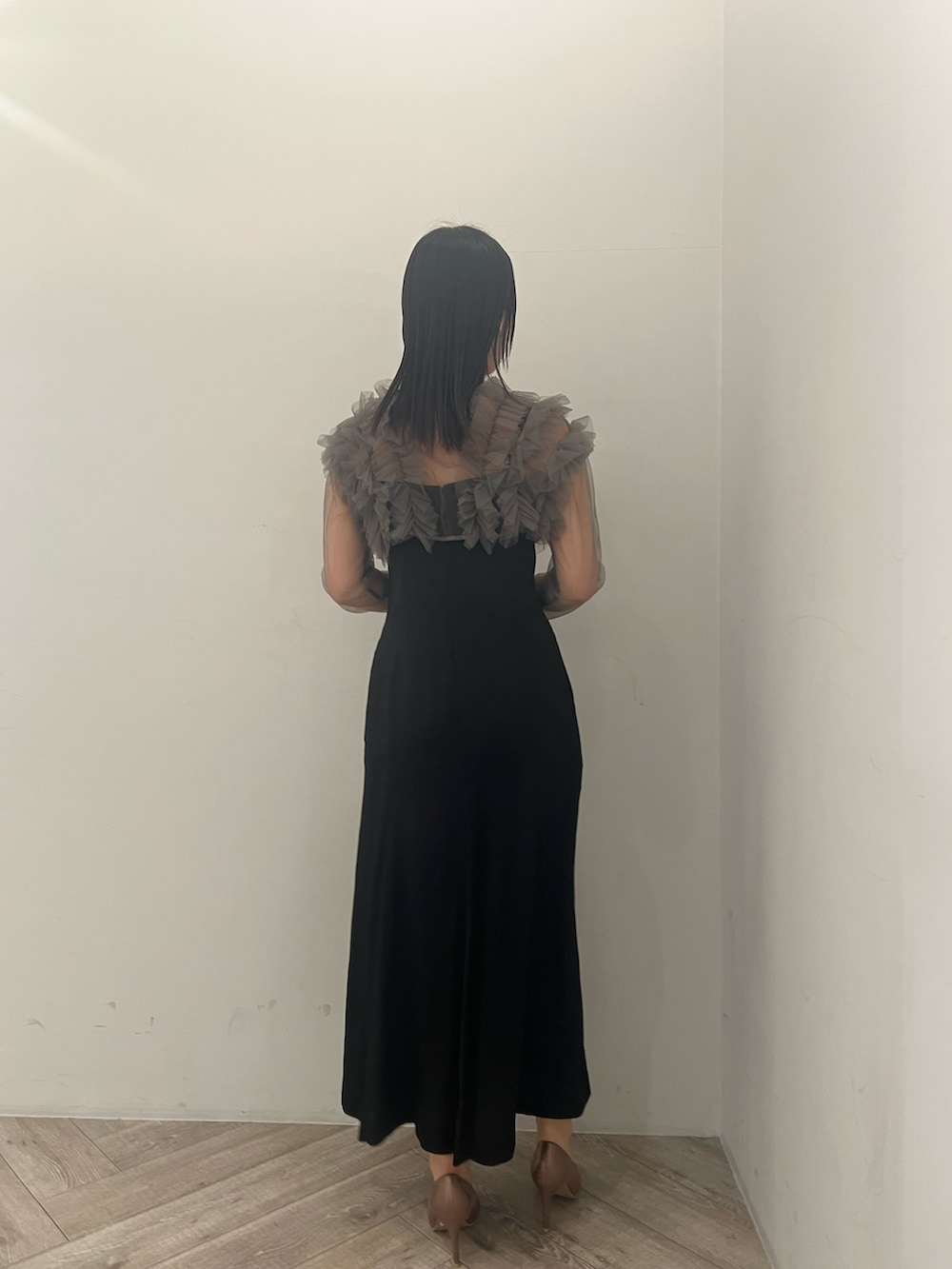 グレー系のドレス、ゴールド系のクラッチバッグ、ゴールド系のパンプスを着用したレディースの春コーディネートの2枚目の写真