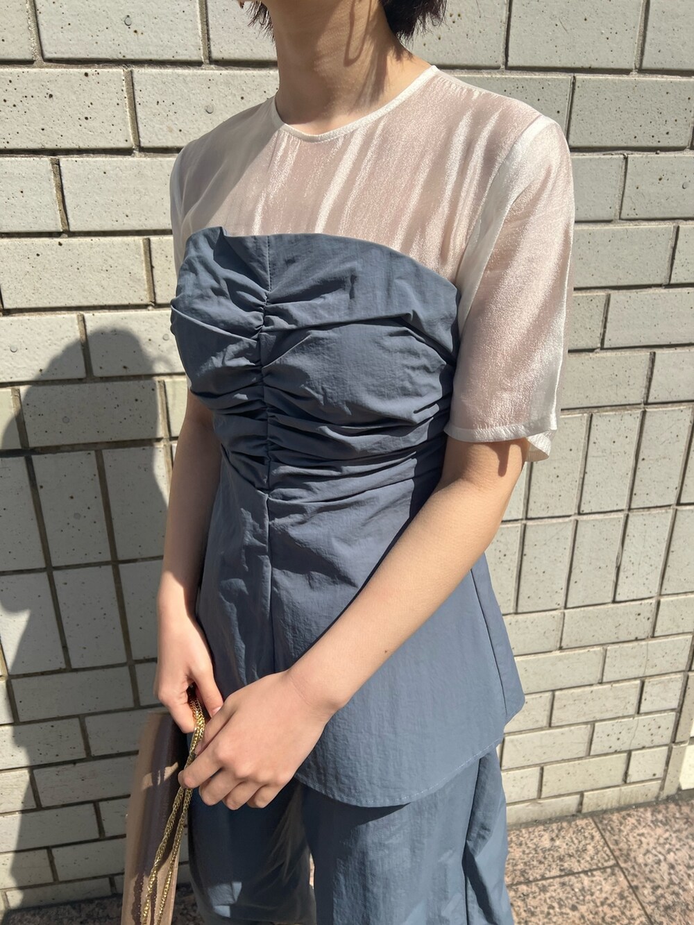 ゴールド系のパンプス、ゴールド系のハンドバッグ、ブルー系のパンツドレスを着用したレディースの春コーディネートの4枚目の写真