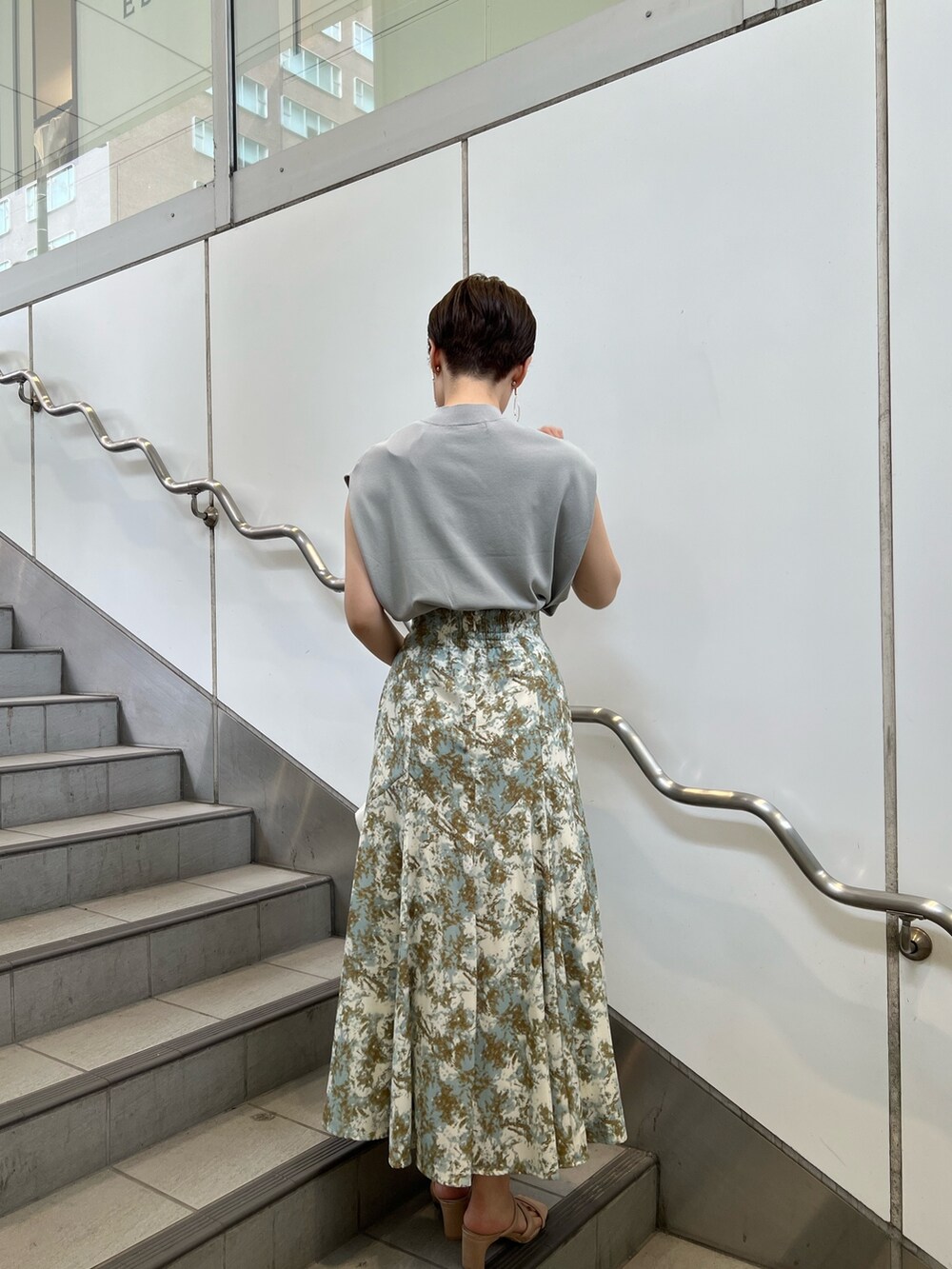 ベージュ系のサンダル、ホワイト系のハンドバッグ、グリーン系のスカートを着用したレディースの夏コーディネートの2枚目の写真