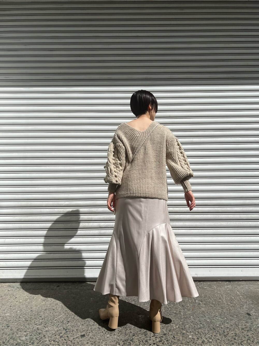 ベージュ系のブーツ、ホワイト系のニット/セーター、グレー系のスカートを着用したレディースの秋コーディネートの3枚目の写真