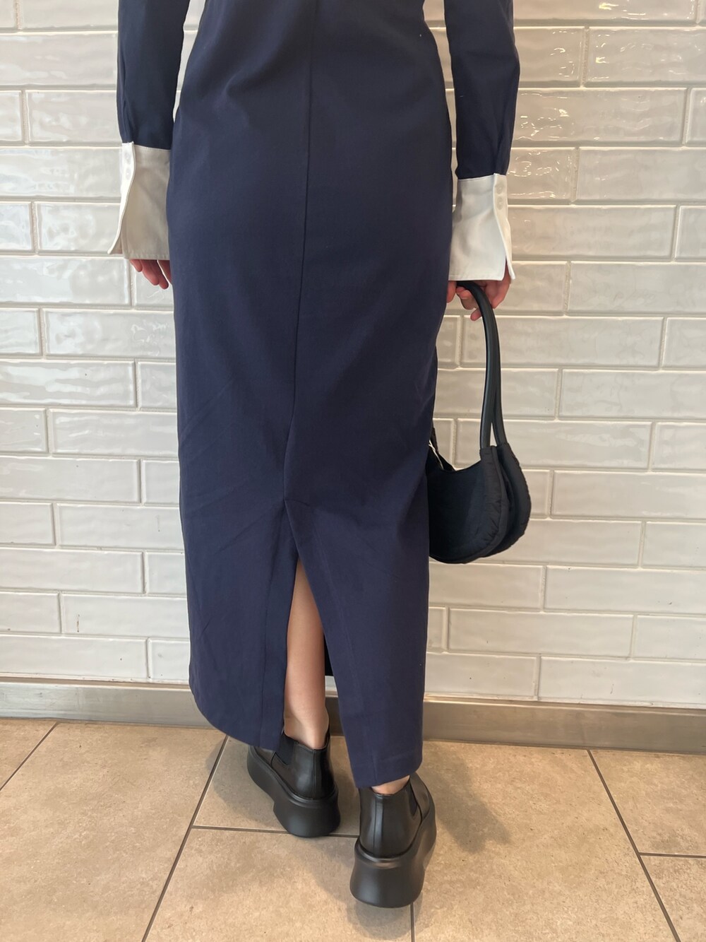 ブラック系のハンドバッグ、ブラック系のブーツ、ブルー系のワンピースを着用したレディースの秋コーディネートの8枚目の写真