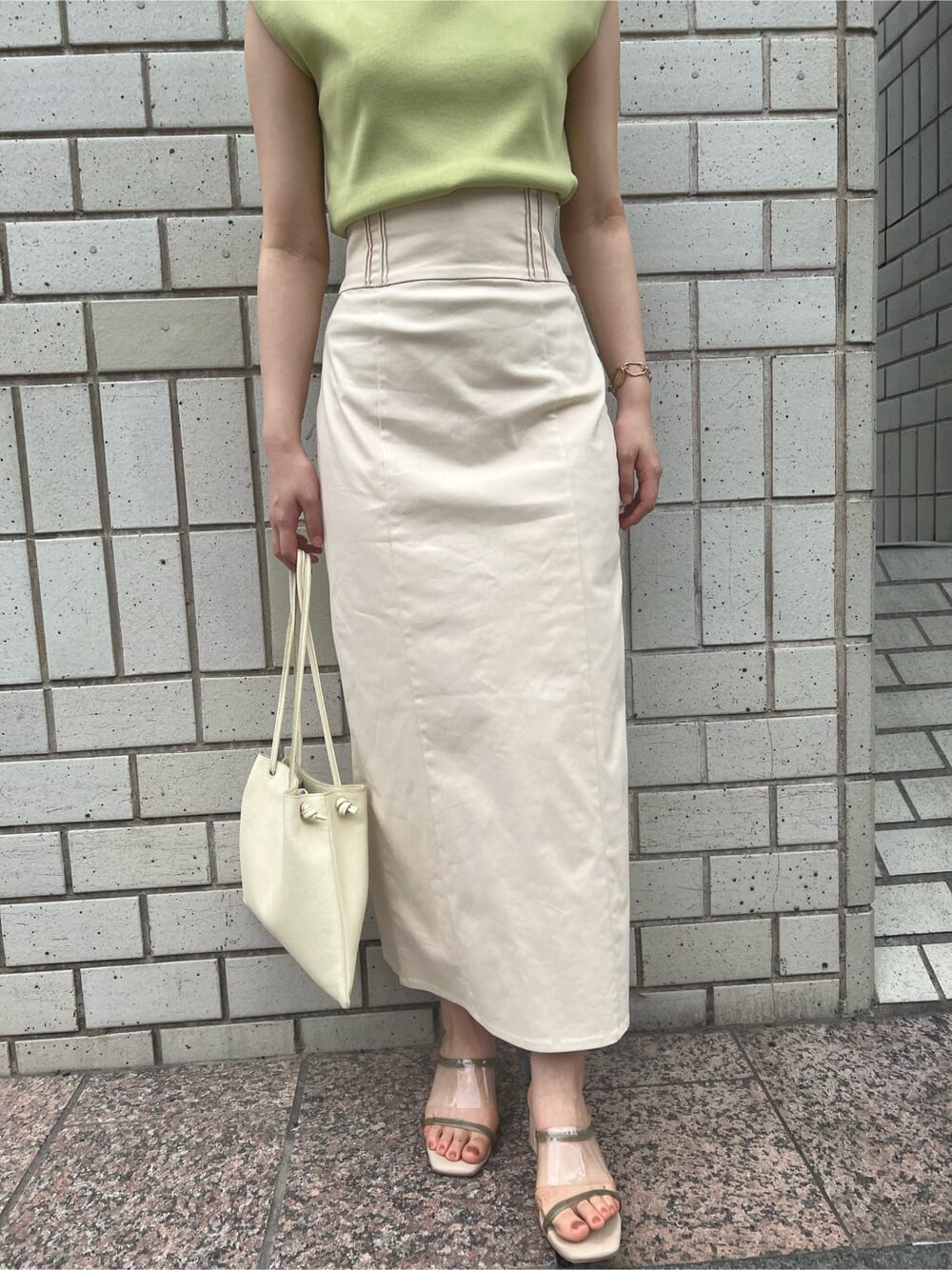 ホワイト系のハンドバッグ、グリーン系のサンダル、ホワイト系のスカートを着用したレディースの春コーディネートの7枚目の写真