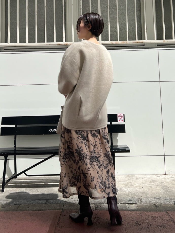 レッド系のブーツ、ホワイト系のカーディガン/ボレロ、ホワイト系のハンドバッグを着用したレディースの秋コーディネートの2枚目の写真