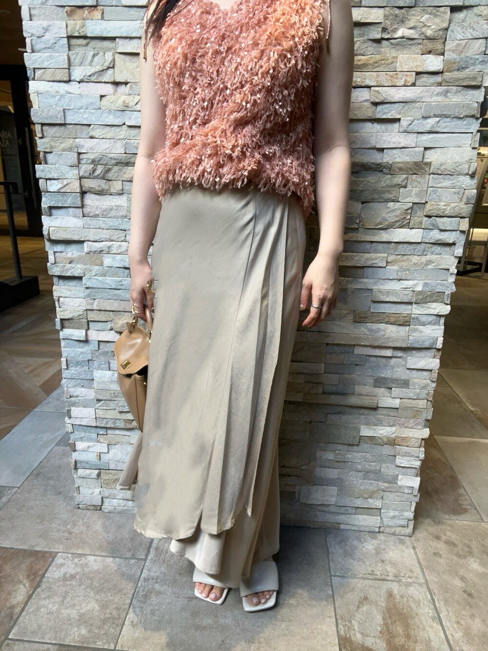 オレンジ系のTシャツ/カットソー、ベージュ系のスカート、ホワイト系のサンダルを着用したレディースの夏コーディネートの4枚目の写真