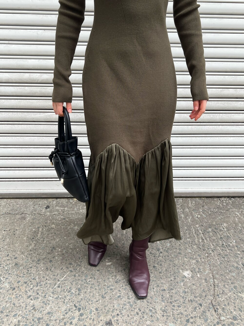 レッド系のブーツ、ブラック系のハンドバッグ、グリーン系のワンピースを着用したレディースの冬コーディネートの7枚目の写真