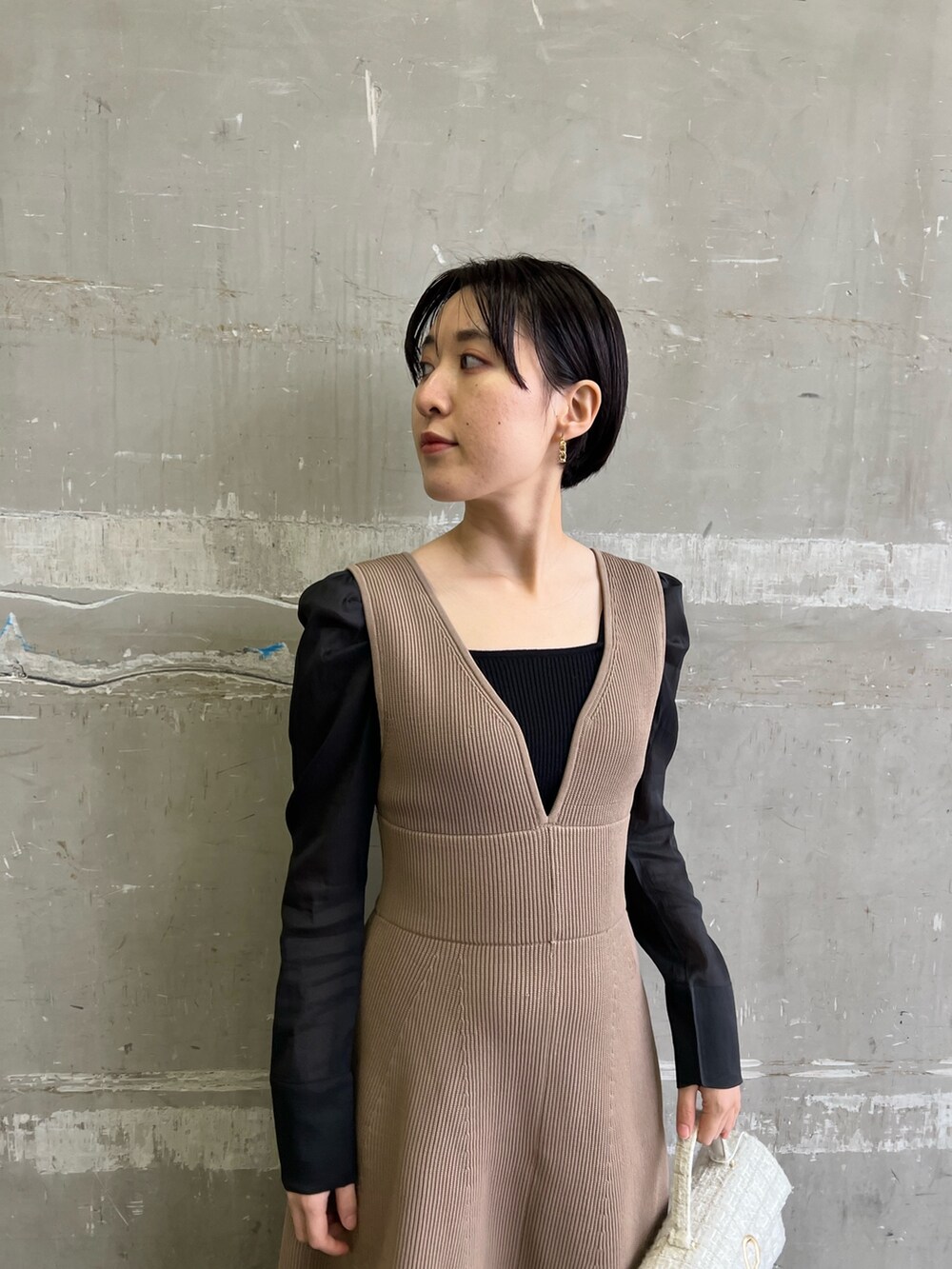 ブラック系のニット/セーター、ホワイト系のショルダーバッグ、ベージュ系のブーツを着用したレディースの冬コーディネートの3枚目の写真