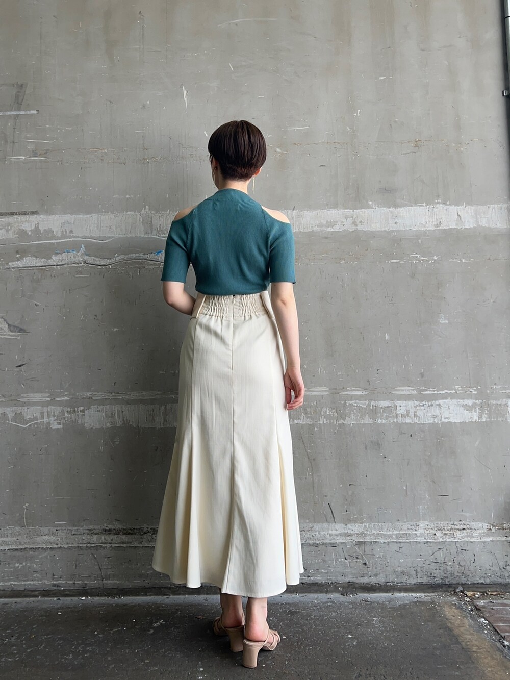 ホワイト系のハンドバッグ、グリーン系のニット/セーター、ホワイト系のスカートを着用したレディースの夏コーディネートの2枚目の写真