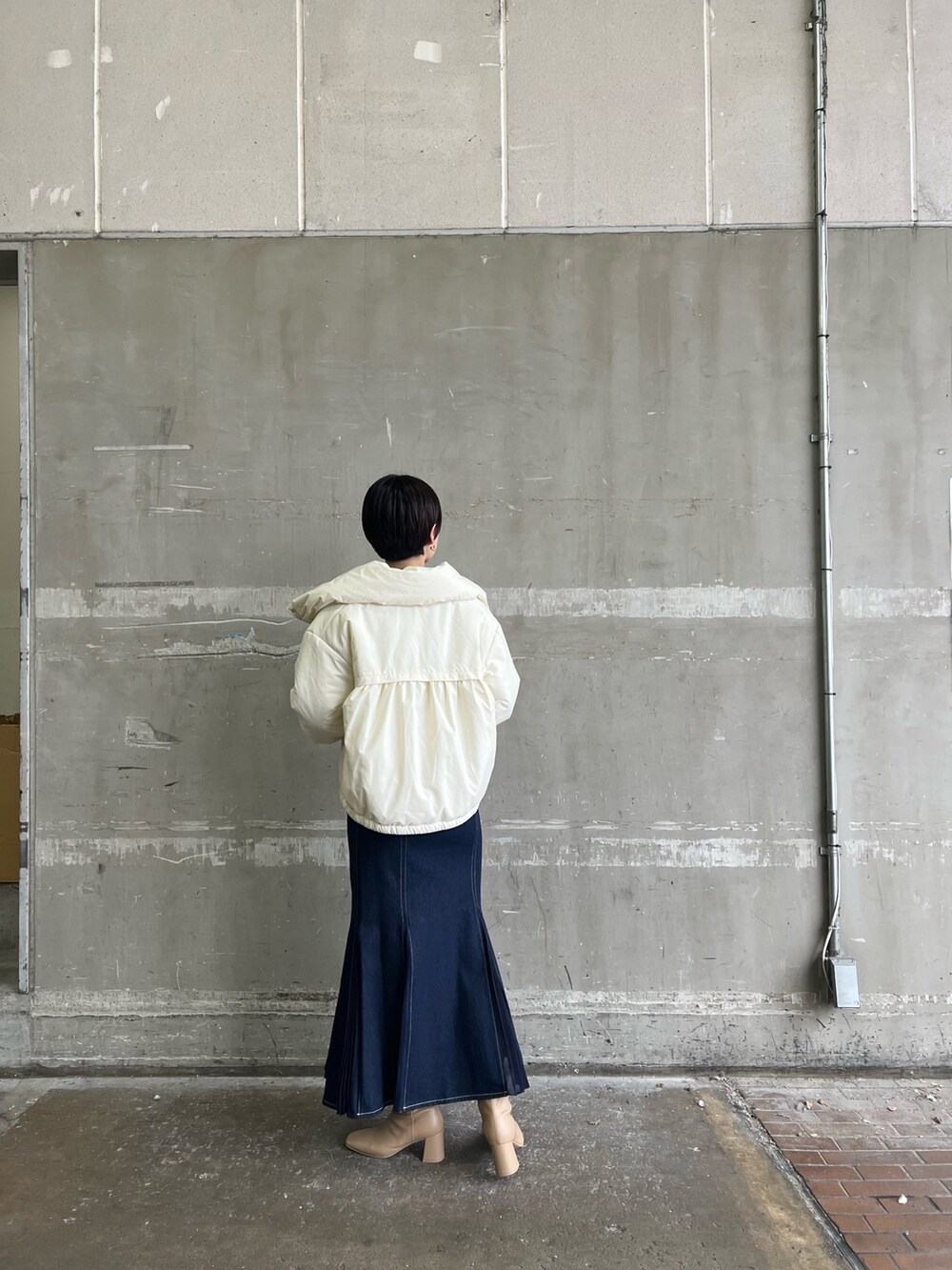 ベージュ系のブーツ、ブルー系のスカート、ホワイト系のダウンジャケット/コートを着用したレディースの冬コーディネートの2枚目の写真