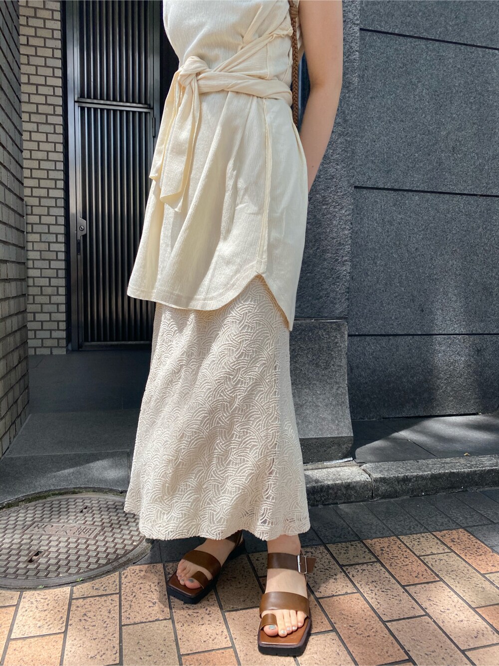 ベージュ系のショルダーバッグ、ホワイト系のスカート、ブラウン系のサンダルを着用したレディースの夏コーディネートの5枚目の写真