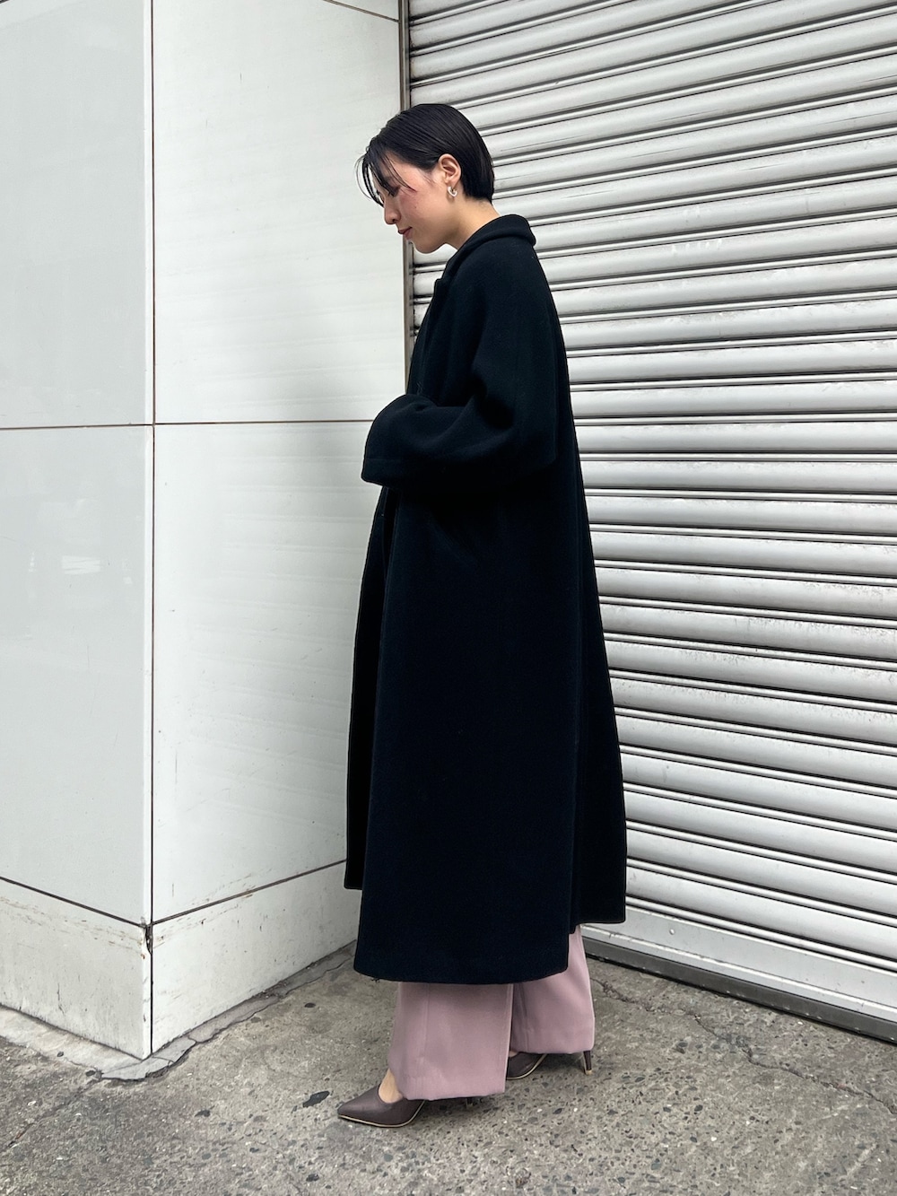 シルバー系のパンプス、ブラック系のチェスターコート、シルバー系のハンドバッグを着用したレディースの冬コーディネートの2枚目の写真