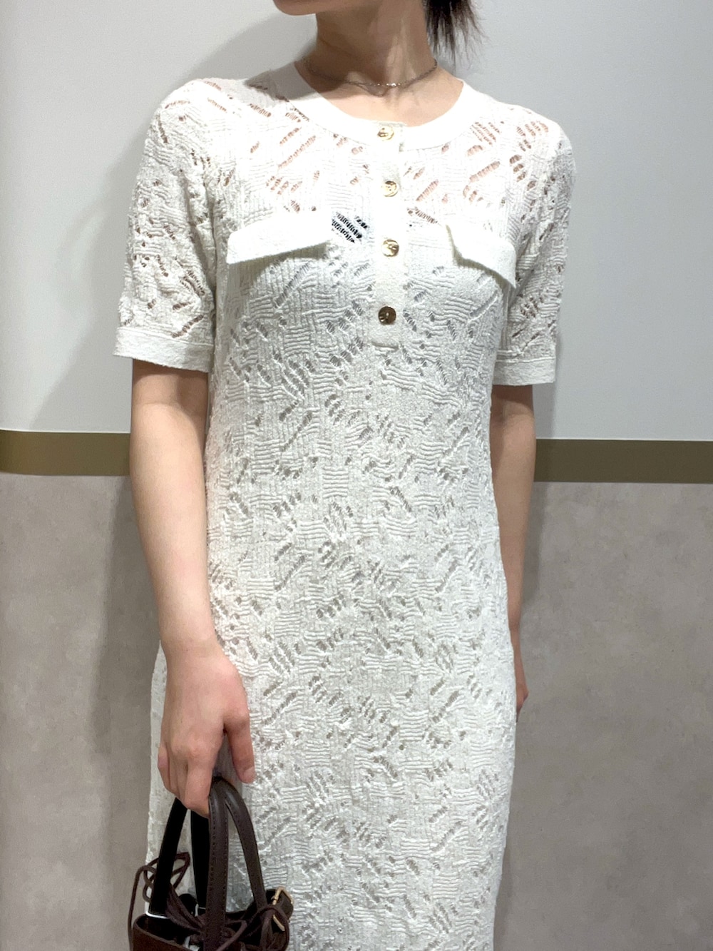 ホワイト系のワンピース、グリーン系のパンプス、ブラウン系のハンドバッグを着用したレディースの春コーディネートの4枚目の写真