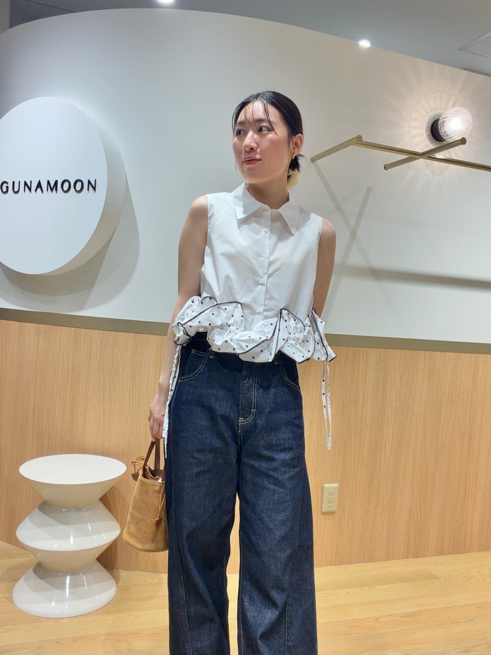 ブルー系のデニムパンツ、オレンジ系のサンダル、ホワイト系のシャツ/ブラウスを着用したレディースの夏コーディネートの3枚目の写真