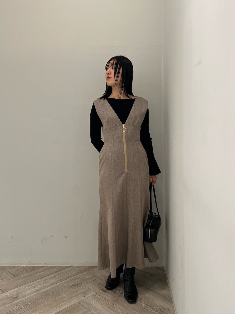 ホワイト系のブルゾン、ベージュ系のジャンパースカート、ブラック系のニット/セーターを着用したレディースの冬コーディネートの7枚目の写真