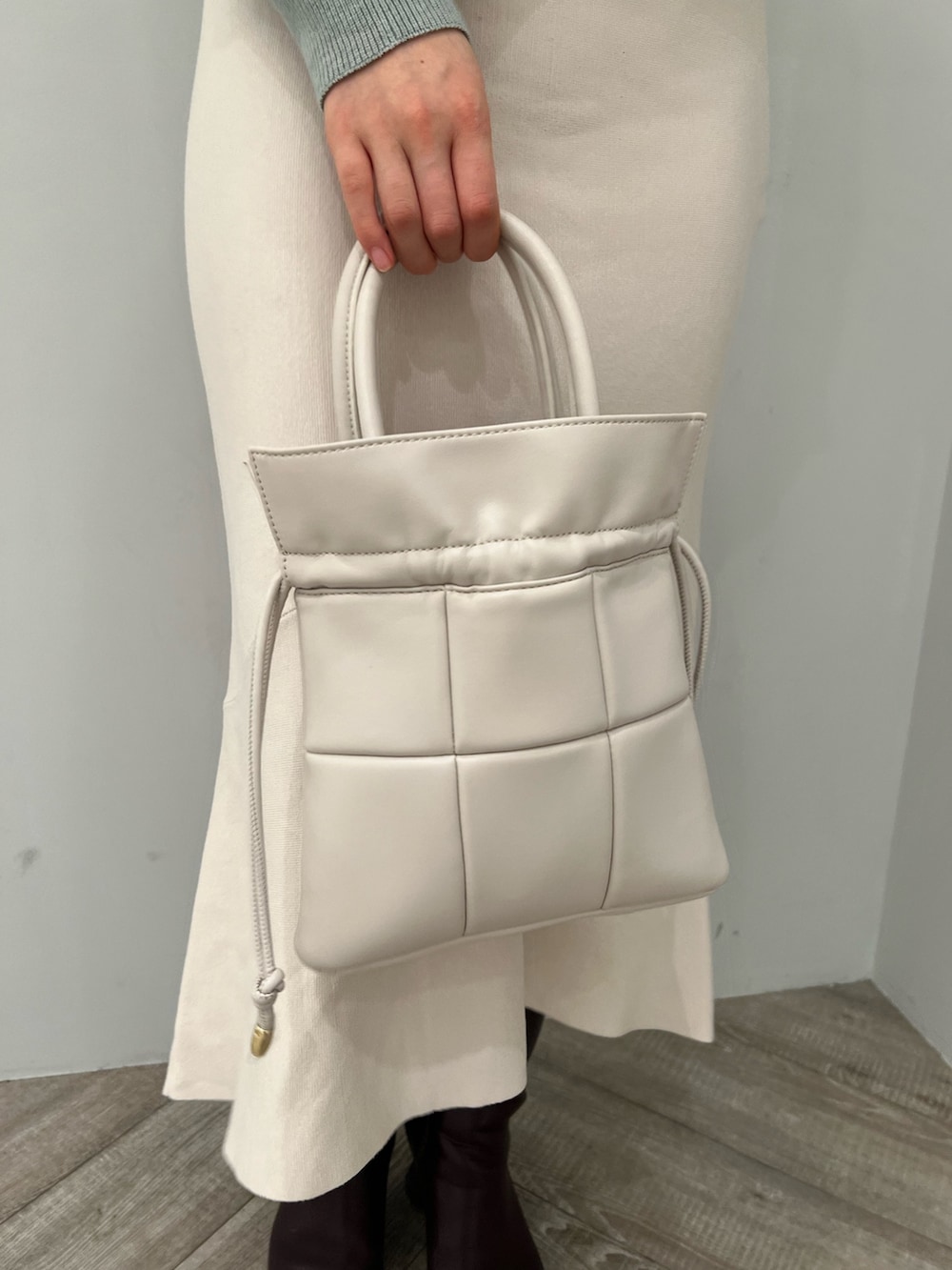 レッド系のブーツ、ホワイト系のハンドバッグ、ホワイト系のスカートを着用したレディースの冬コーディネートの10枚目の写真