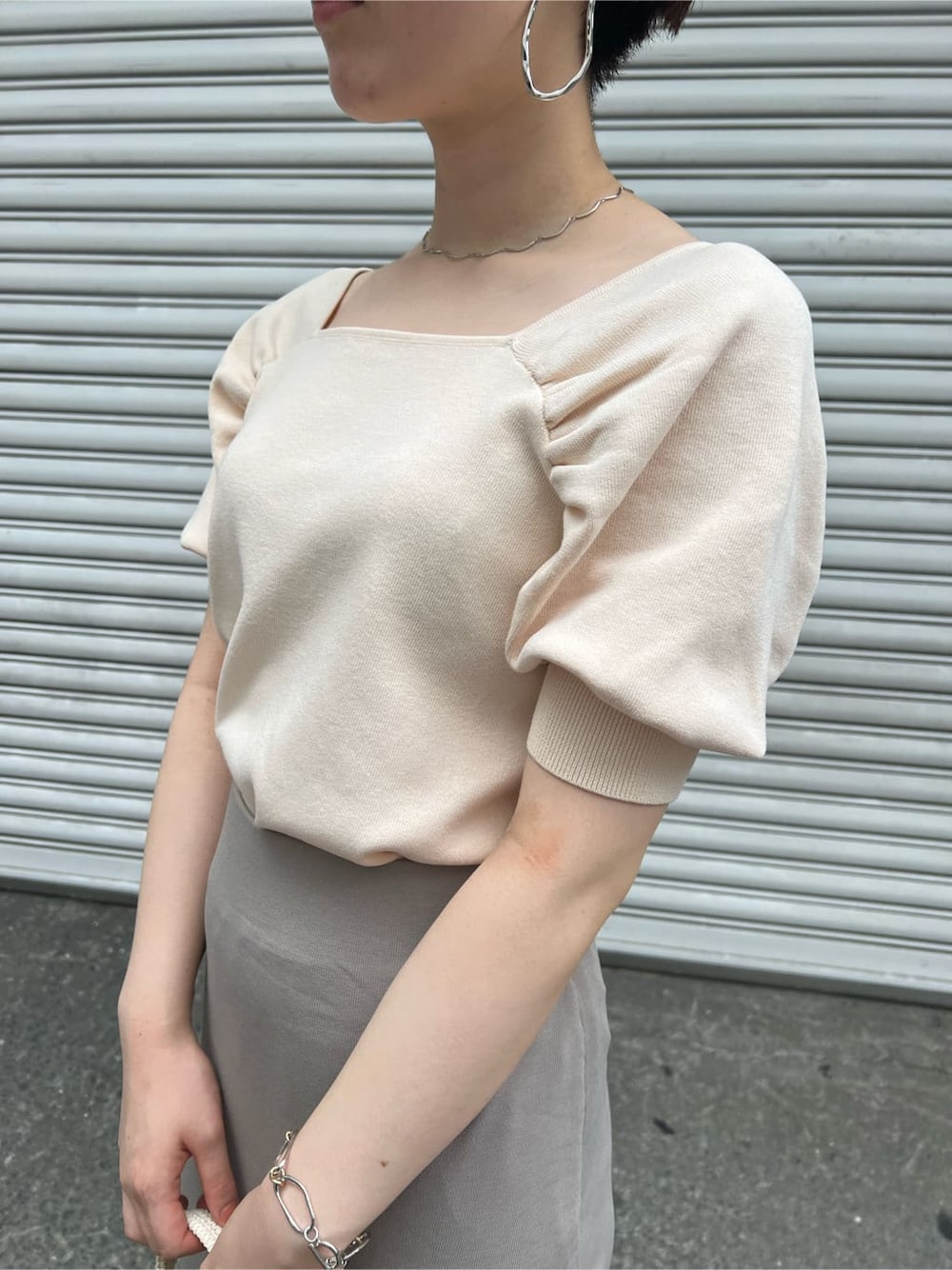 ブラウン系のパンプス、ホワイト系のニット/セーター、ホワイト系のハンドバッグを着用したレディースの夏コーディネートの5枚目の写真