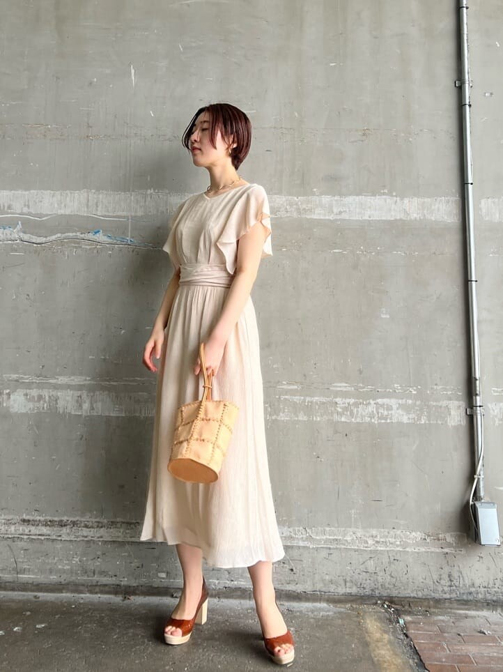 ホワイト系のワンピース、ブラウン系のパンプス、オレンジ系のショルダーバッグを着用したレディースの春コーディネートの3枚目の写真