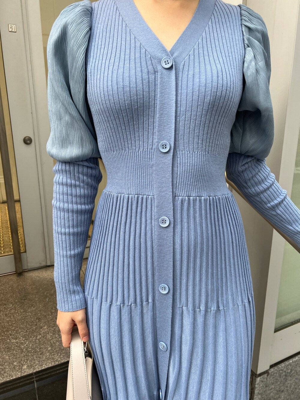 ベージュ系のブーツ、ホワイト系のハンドバッグ、ホワイト系のノーカラーコートを着用したレディースの冬コーディネートの7枚目の写真