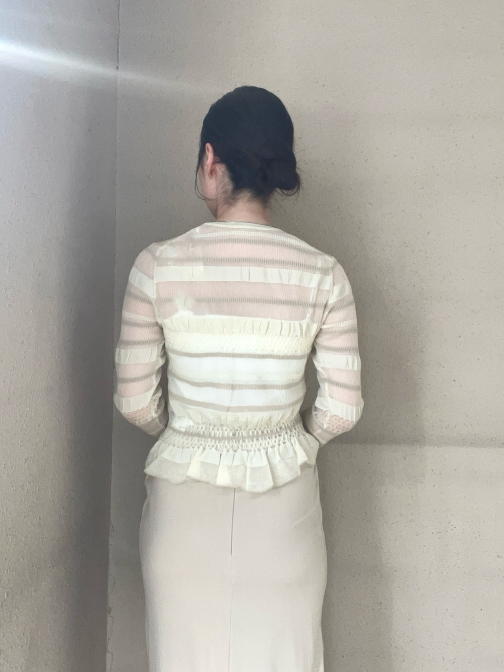 ベージュ系のスカート、ホワイト系のニット/セーター、ホワイト系のスニーカーを着用したレディースの春コーディネートの5枚目の写真