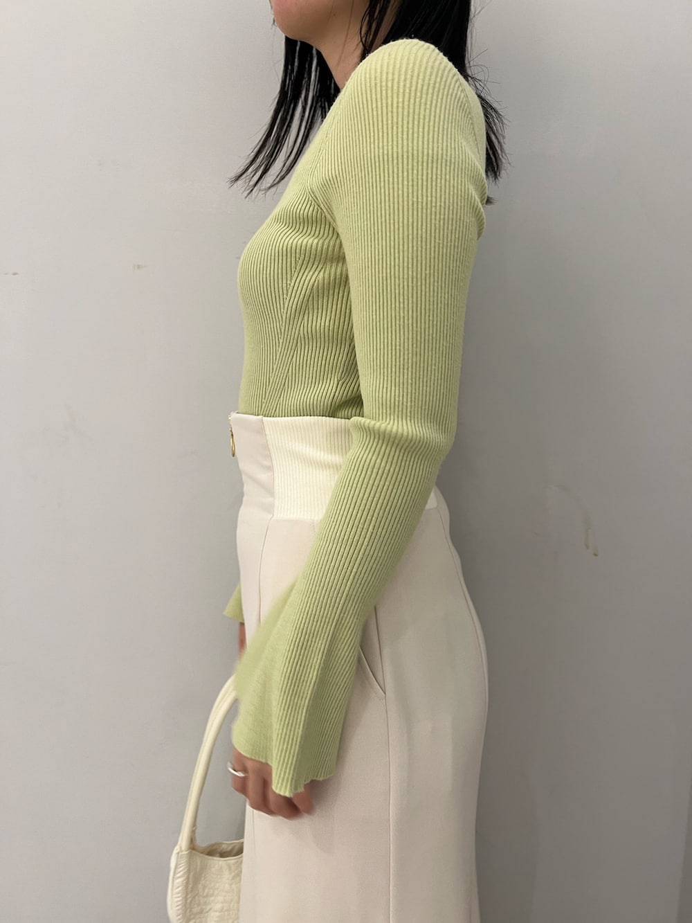 グリーン系のニット/セーター、ホワイト系のスカートを着用したレディースの冬コーディネートの6枚目の写真