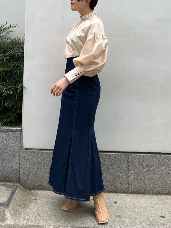 ベージュ系のシャツ/ブラウス、ベージュ系のブーツ、ブルー系のスカートを着用したレディースの春コーディネートの3枚目の写真