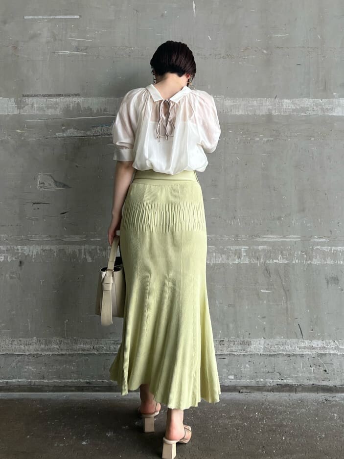 ホワイト系のハンドバッグ、グリーン系のサンダル、イエロー系のスカートを着用したレディースの夏コーディネートの3枚目の写真