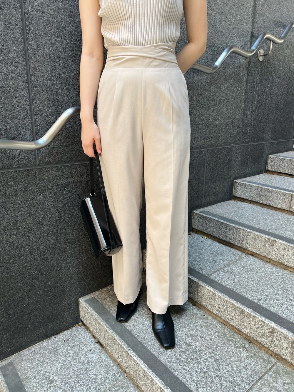 ブラック系のショルダーバッグ、ブラック系のブーツ、ホワイト系のスラックスを着用したレディースの秋コーディネートの9枚目の写真