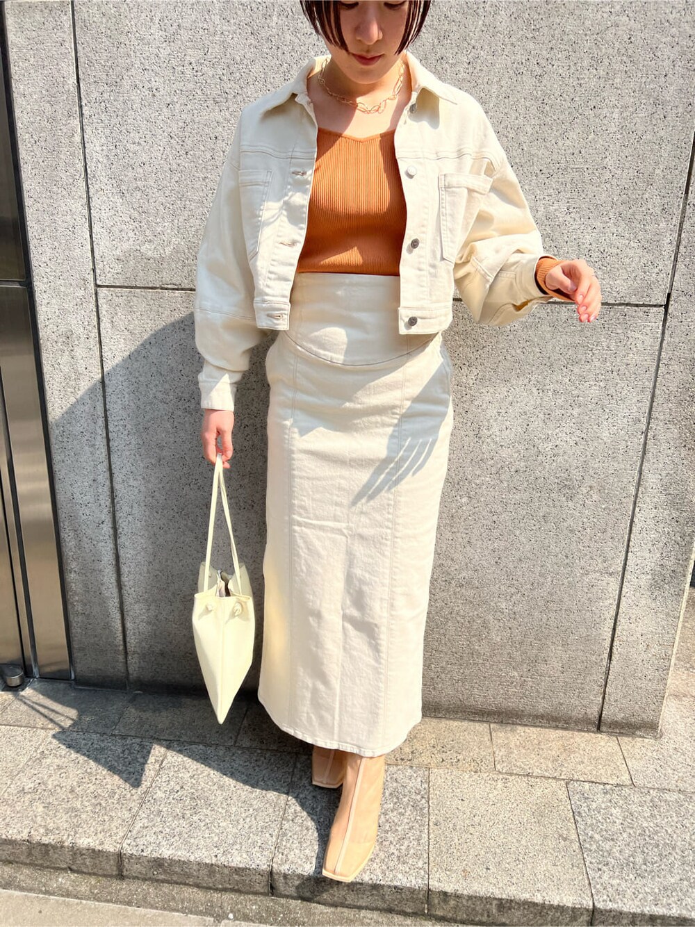 ホワイト系のハンドバッグ、ホワイト系のブルゾン、ホワイト系のスカートを着用したレディースの春コーディネートの4枚目の写真
