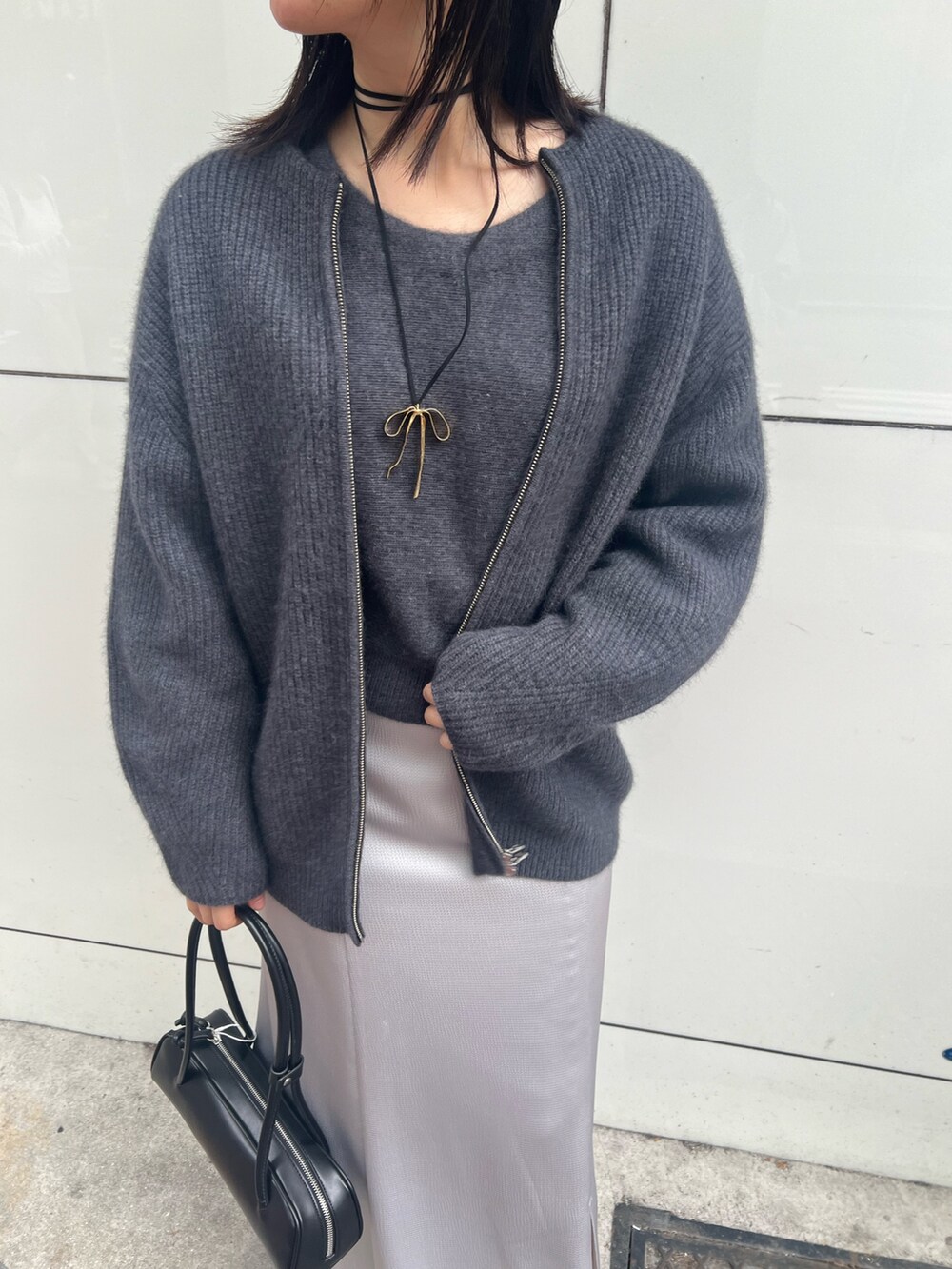 グレー系のニット/セーター、グレー系のカーディガン/ボレロ、ブラック系のスカートを着用したレディースの秋コーディネートの2枚目の写真